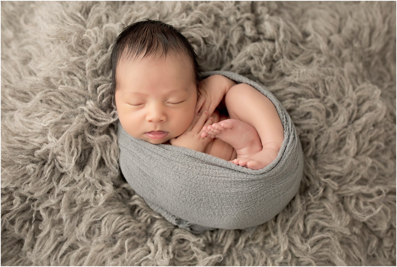 Newborn boy in gray wrap | Photo by Idalia Photography