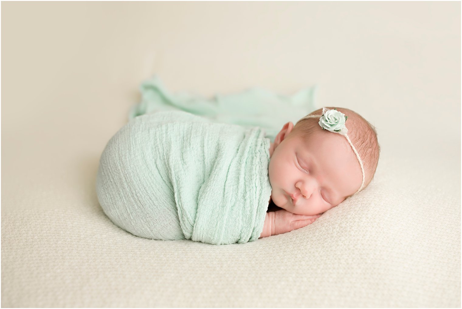Newborn baby in mint green wrap