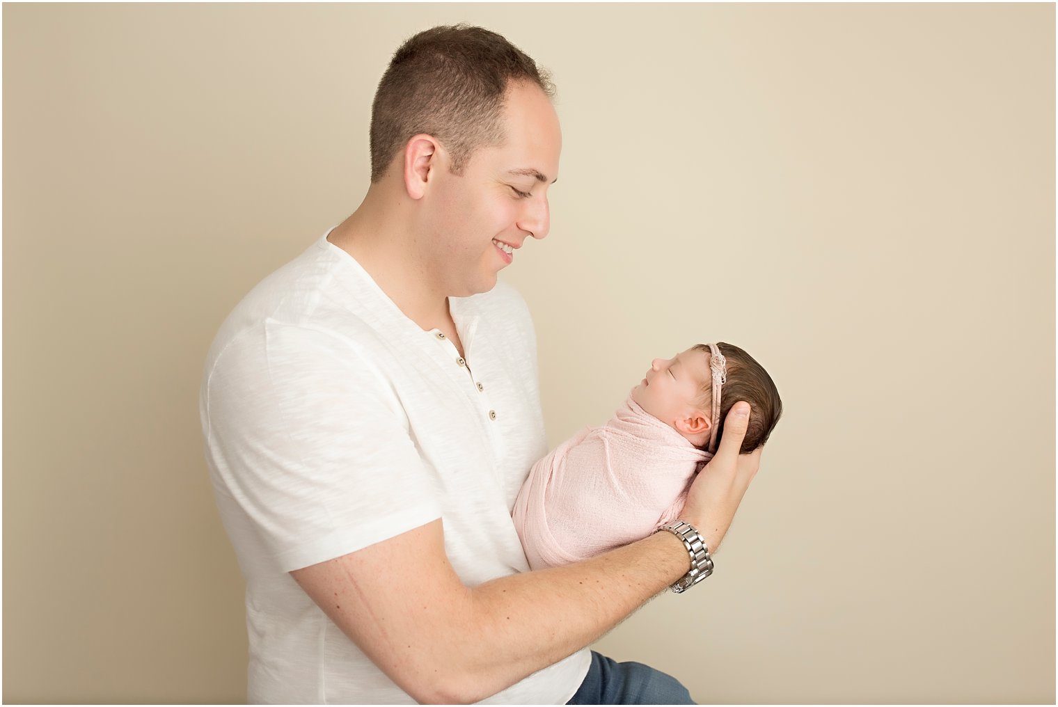 Father and newborn daughter in white and pink color palette
