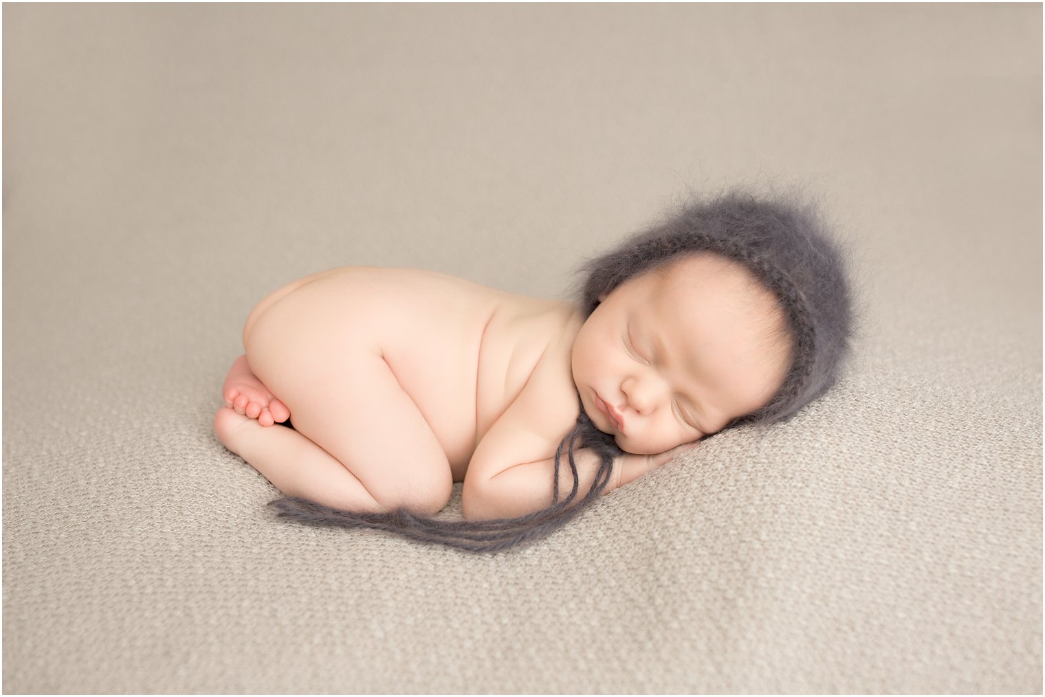 Newborn boy in tushie up pose and fuzzy hat