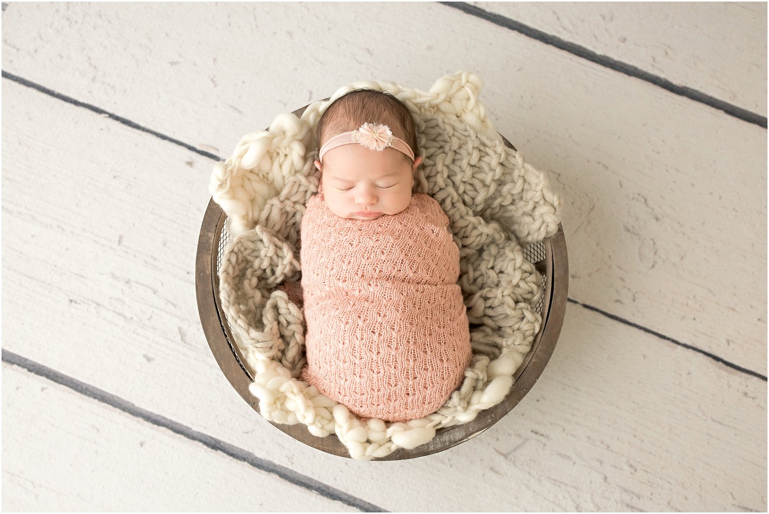 Baby swaddled and placed in a wooden bowl