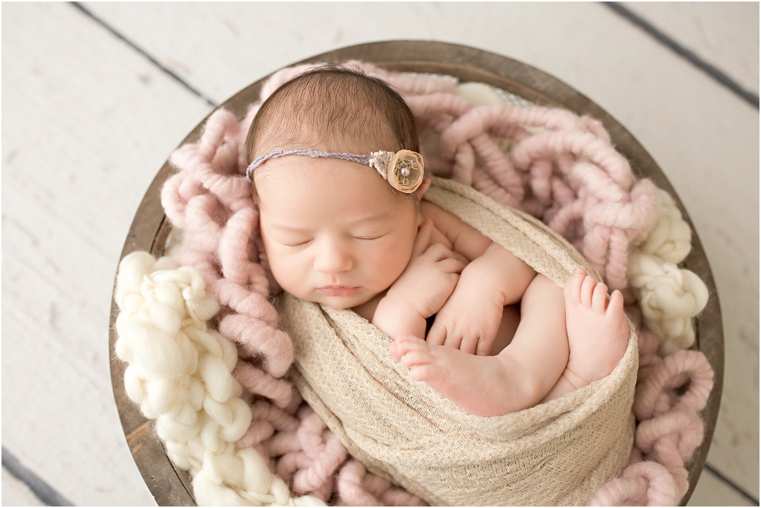 Newborn girl swaddled in a wood basket