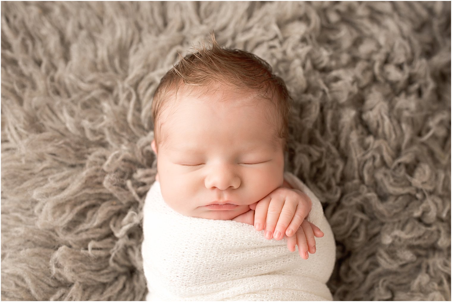 Newborn boy swaddled in white wrap