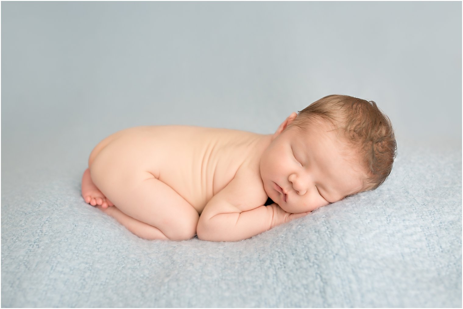 Newborn boy on soft blue blanket