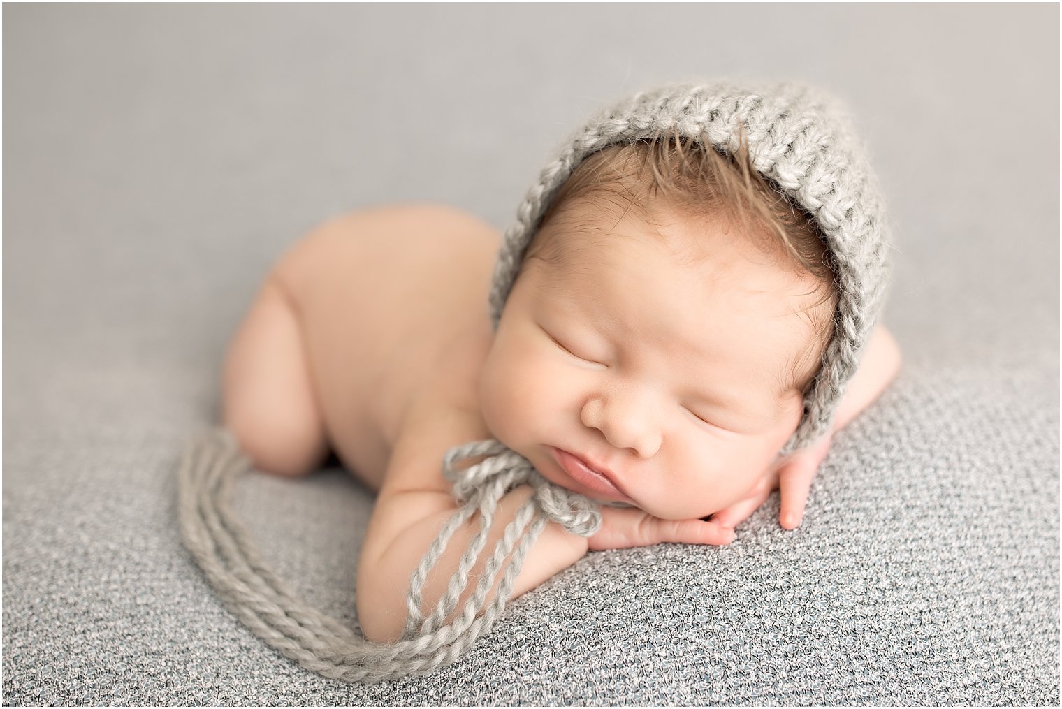 Newborn boy in chin on hands pose