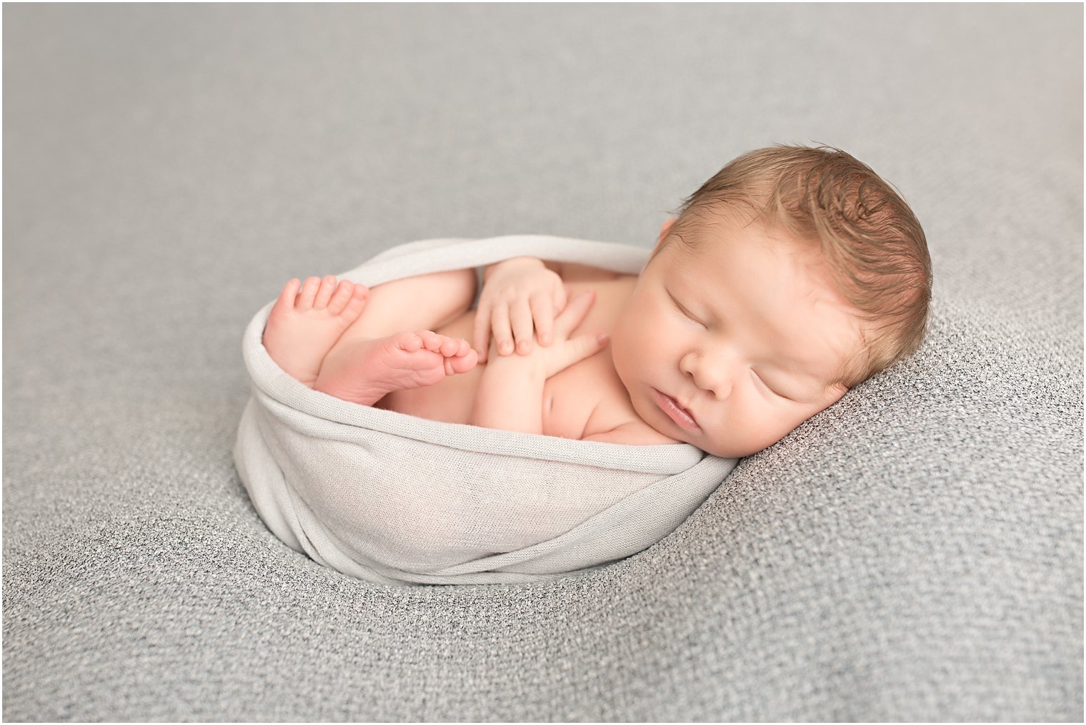 Newborn boy wrapped in gray blanket