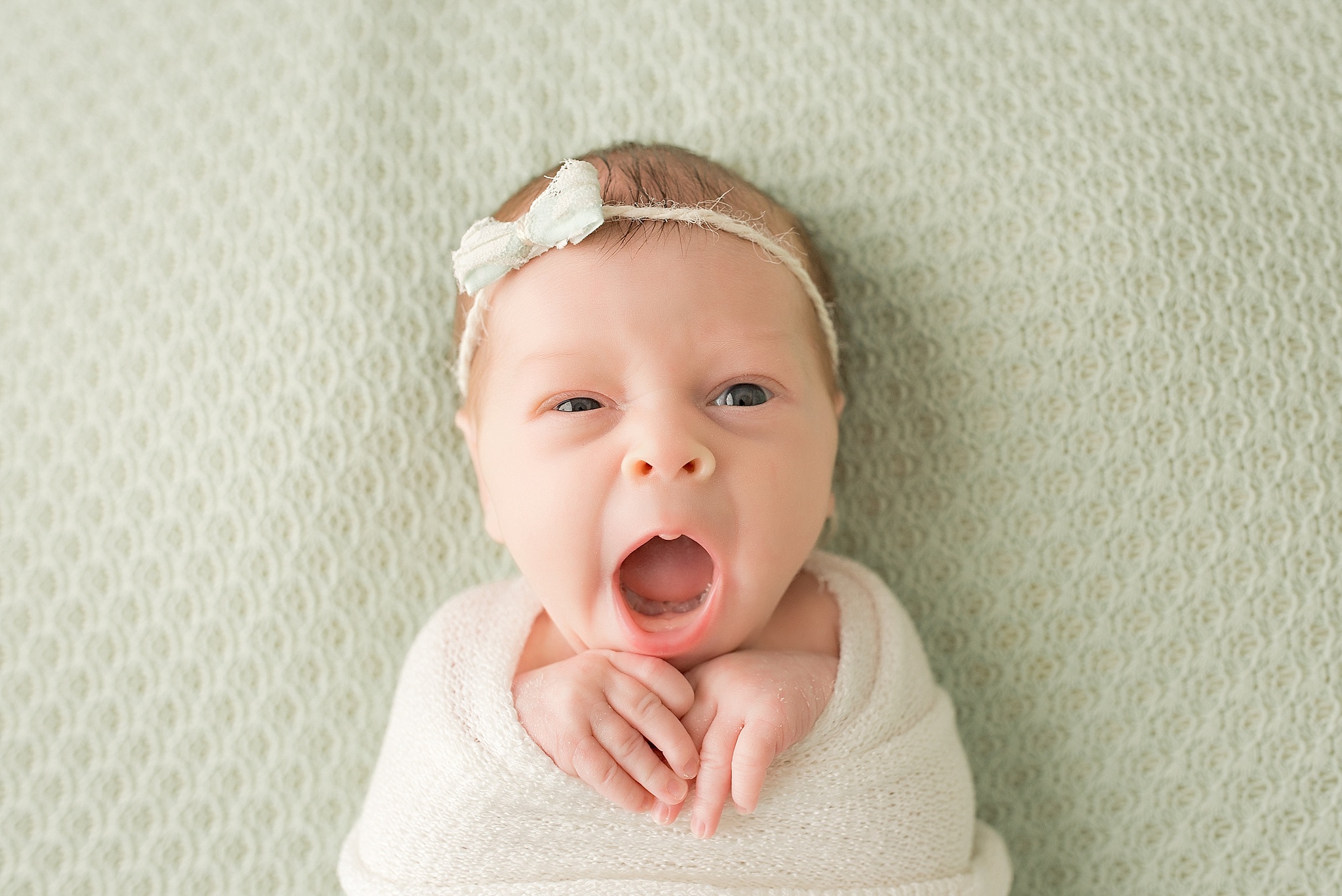 baby girl yawning on green blanket