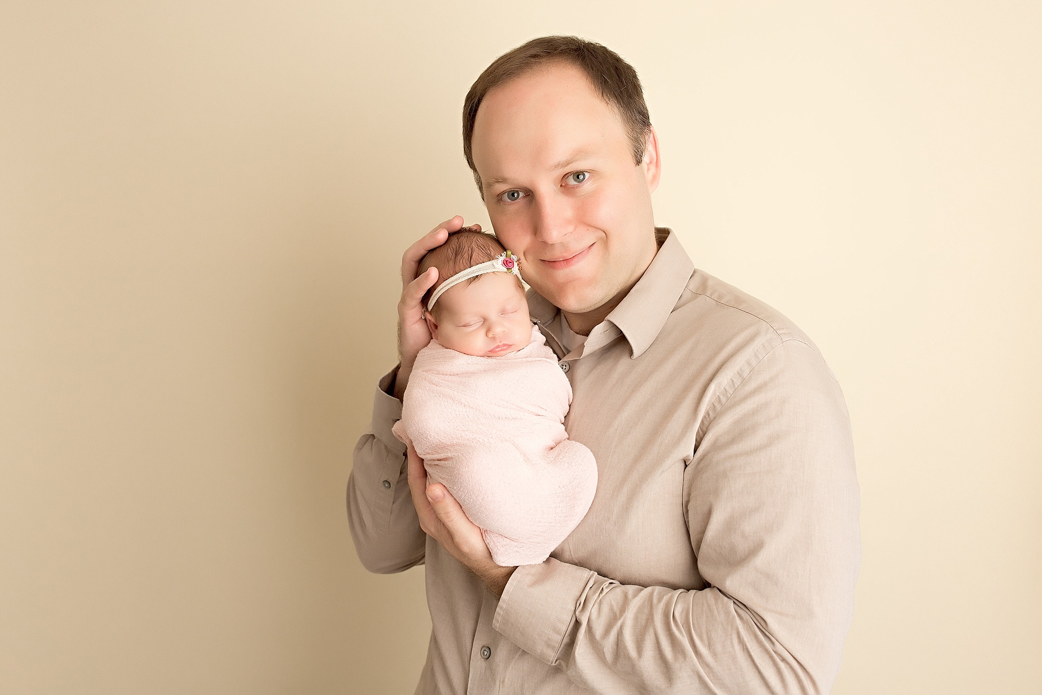 proud dad holds baby girl in pink wrap