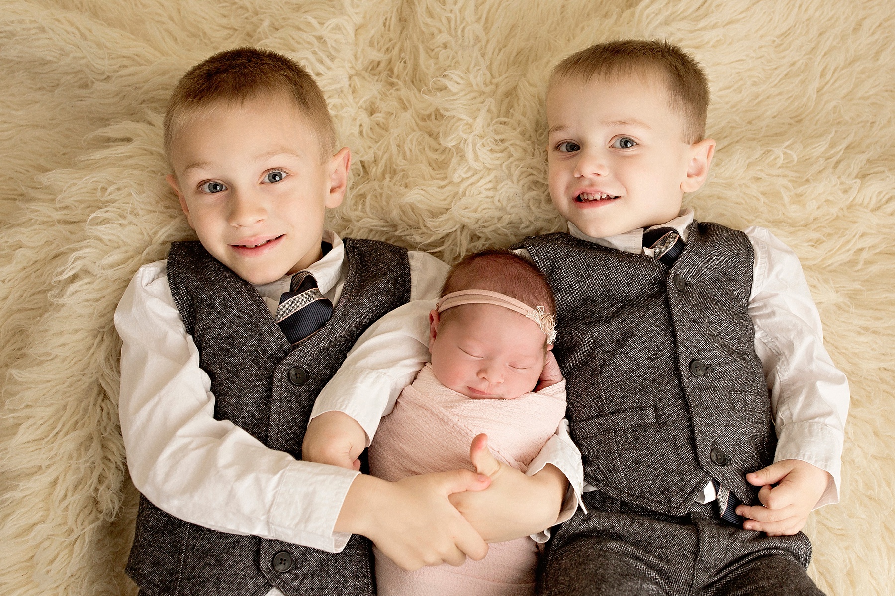 two big brothers holding sleeping newborn baby girl