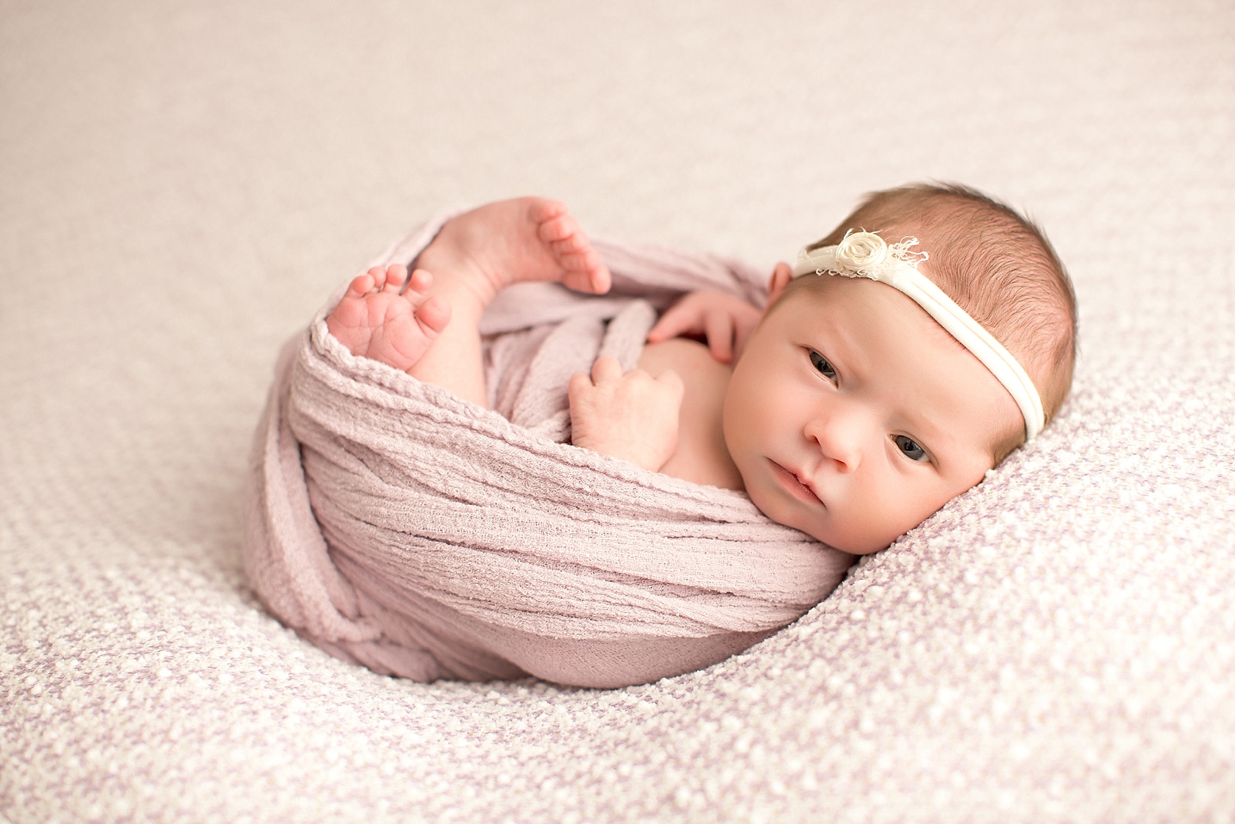 baby girl with pink wrap during studio newborn shoot