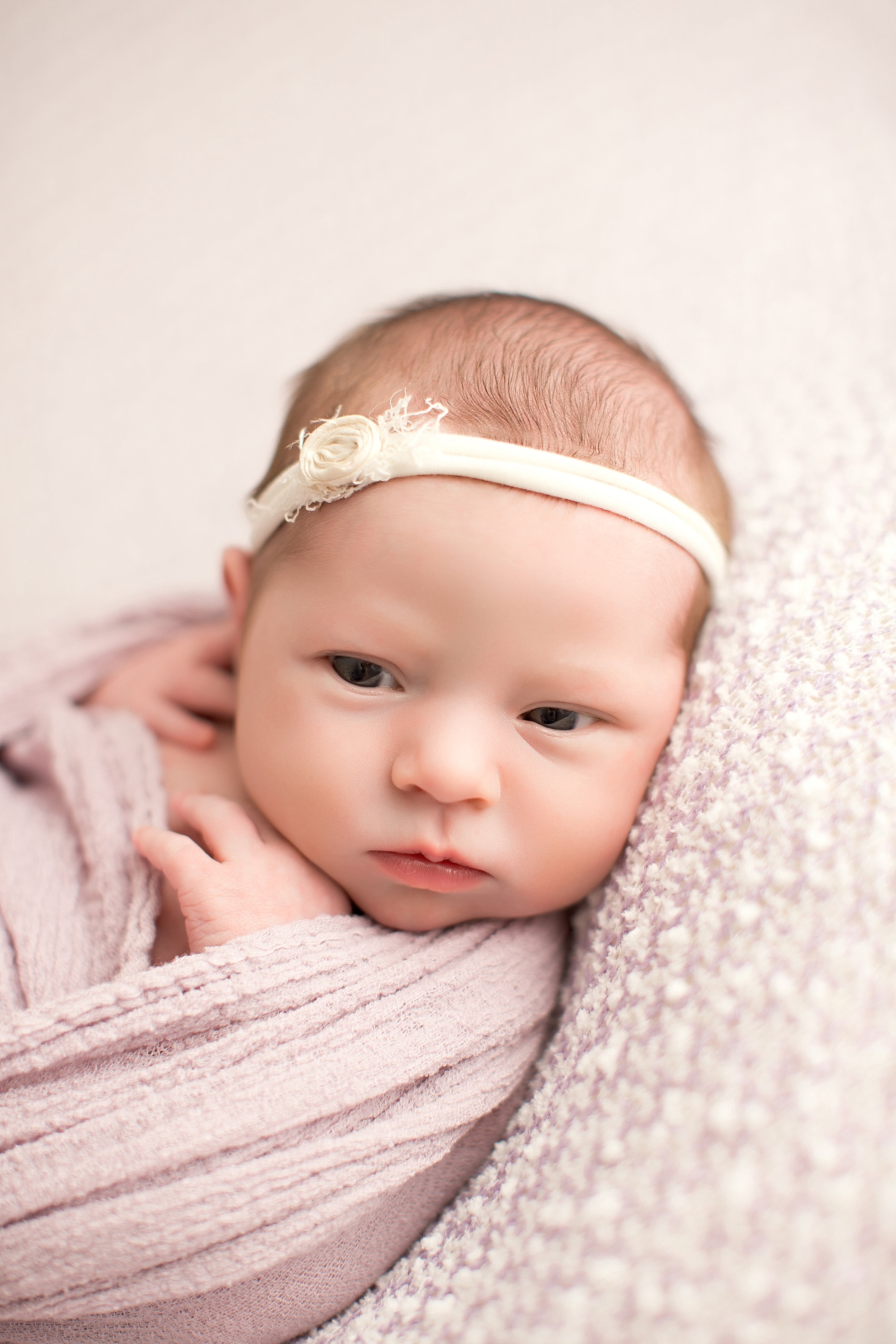 newborn baby girl with ivory headband and pink wrap