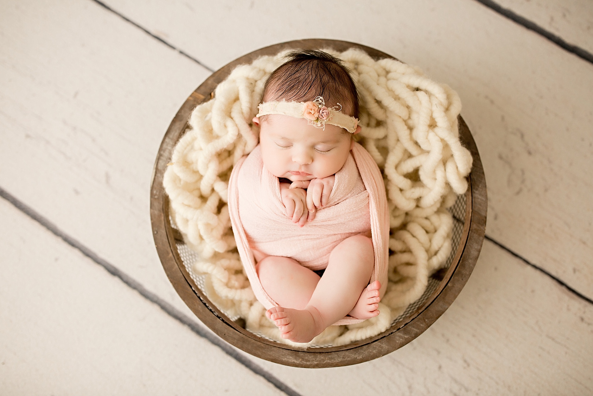 baby girl in basket with ivory blanket