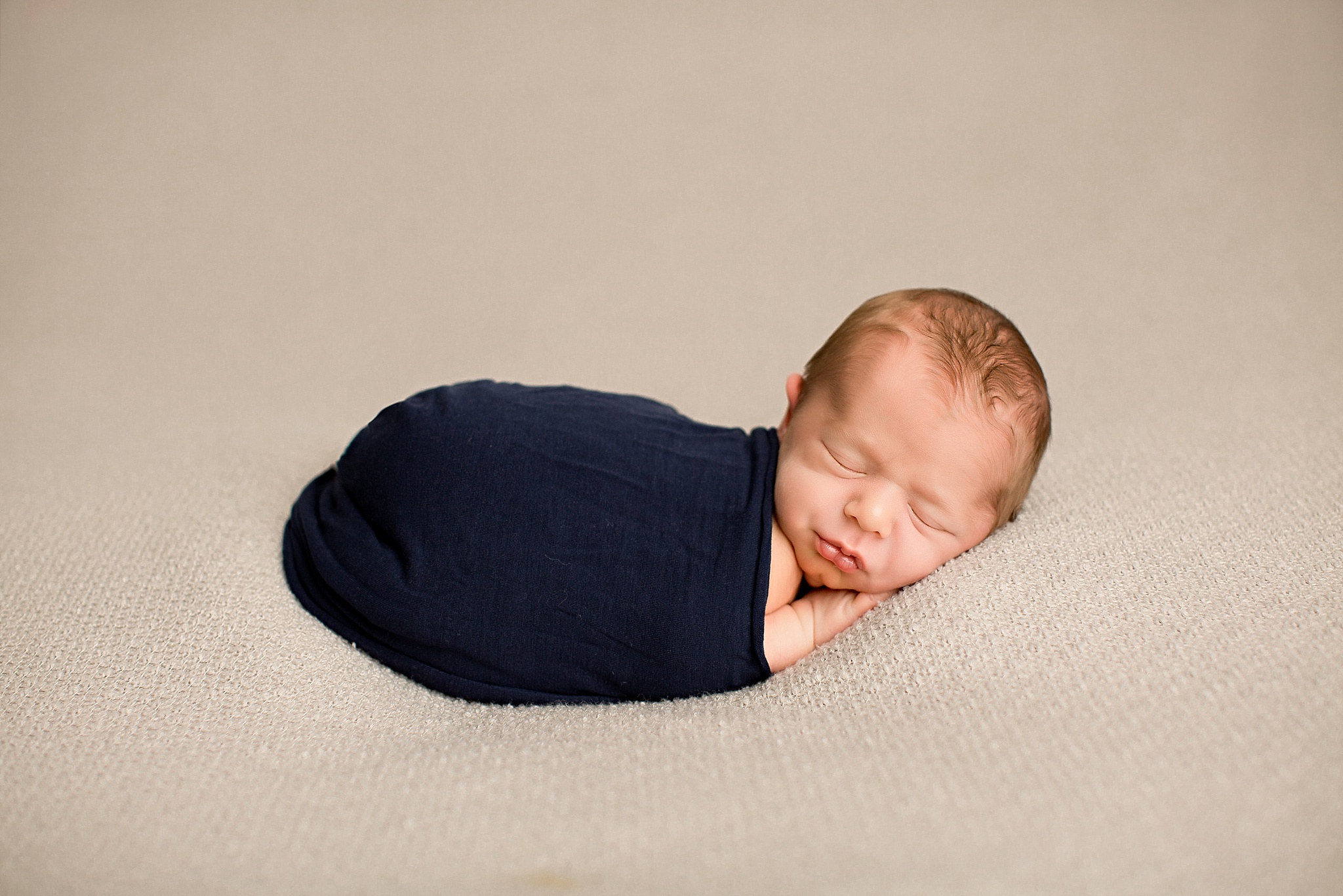 sleeping baby boy in navy wrap during newborn session
