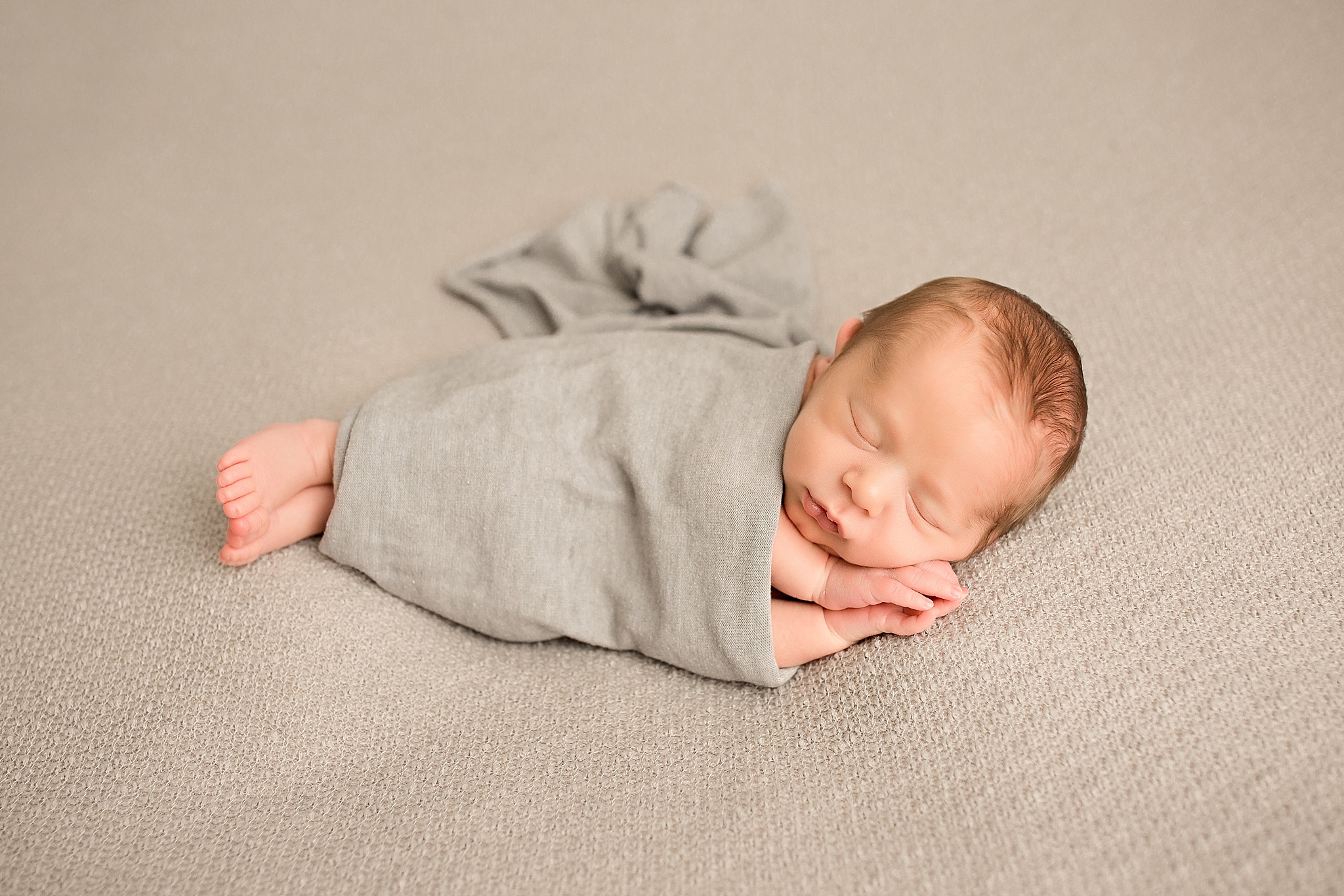 baby boy in grey wrap during newborn session 