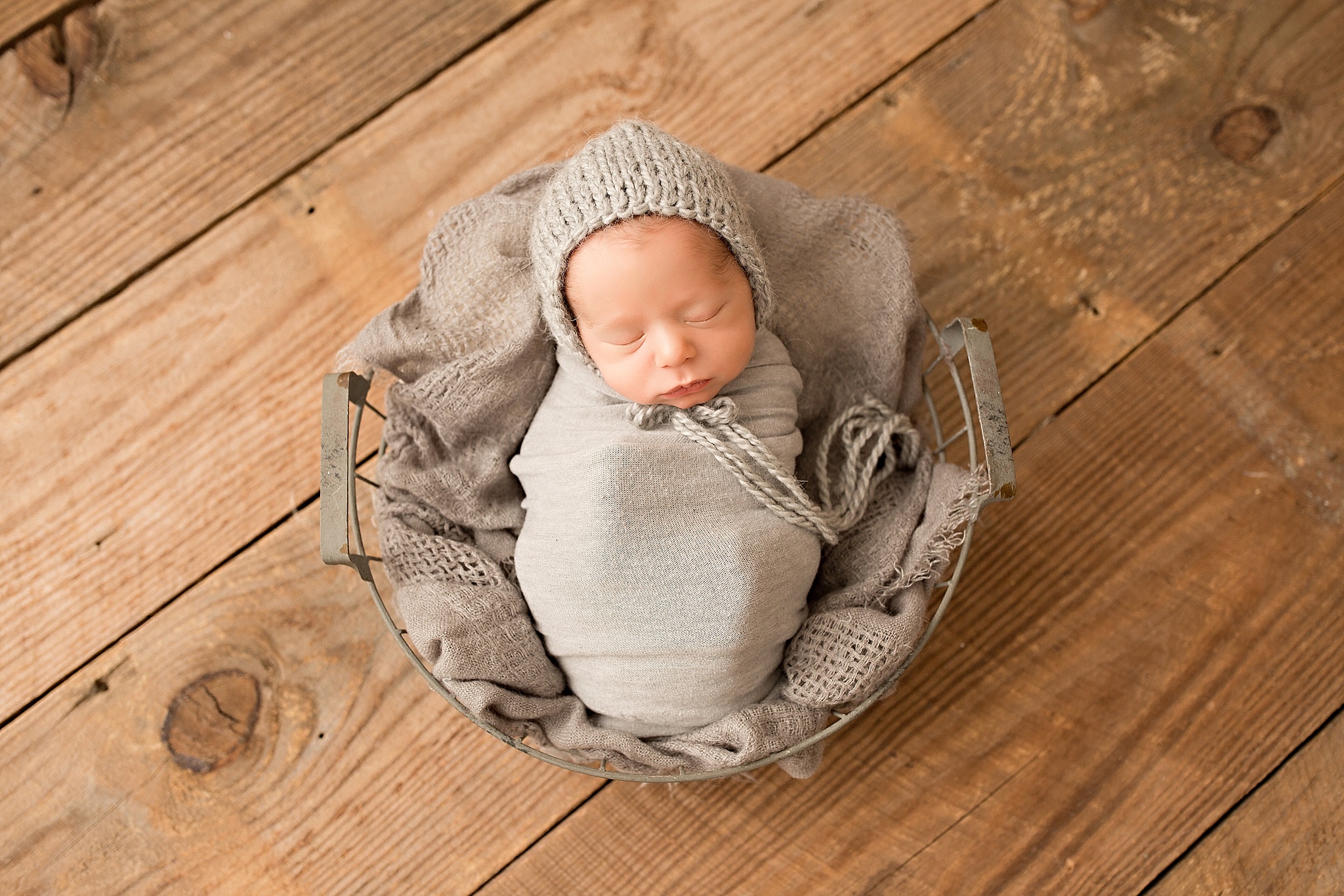 sleeping baby boy in grey hat and basket 