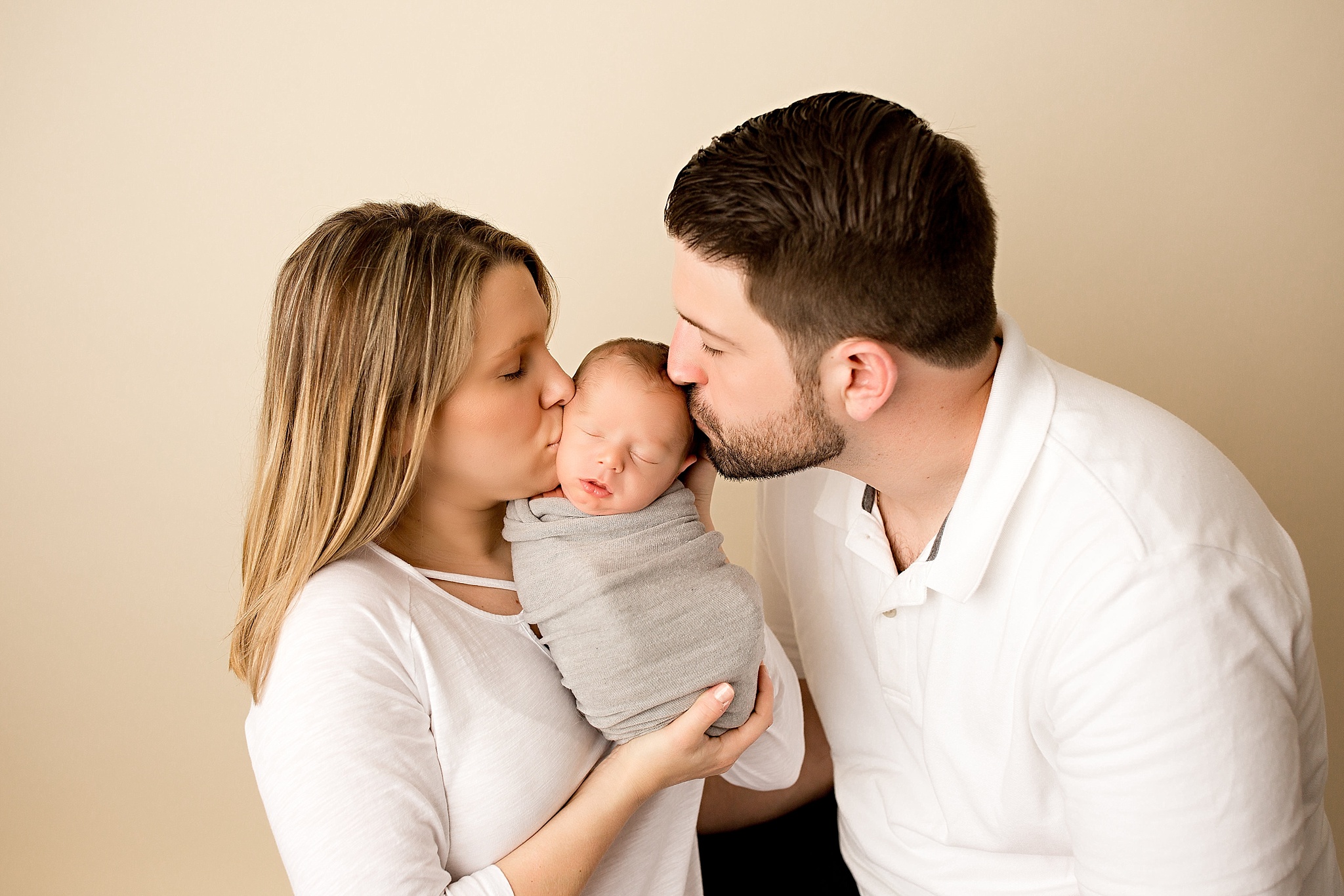new mom and dad kissing baby boy during newborn session
