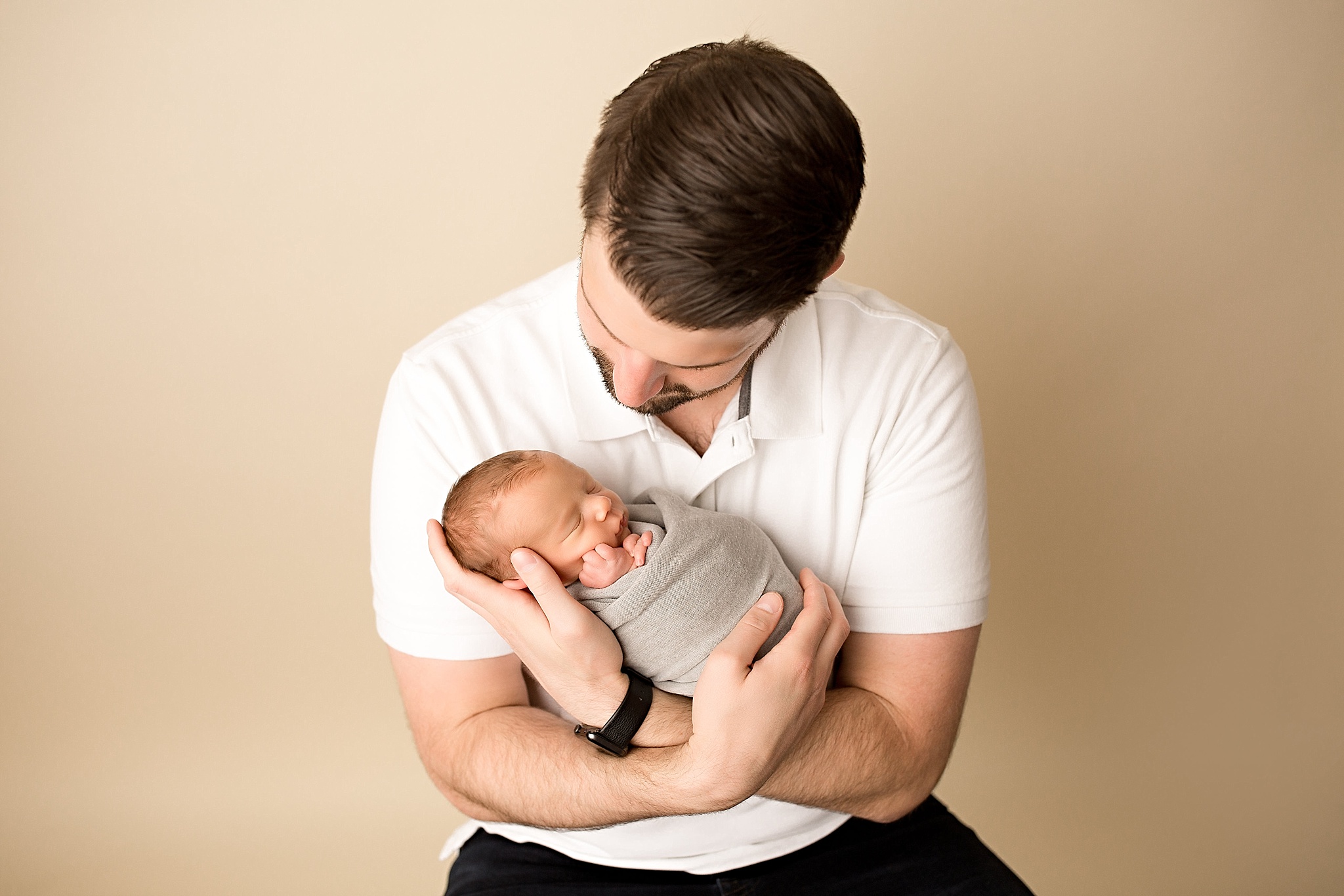 new dad holds sleeping baby boy during newborn session