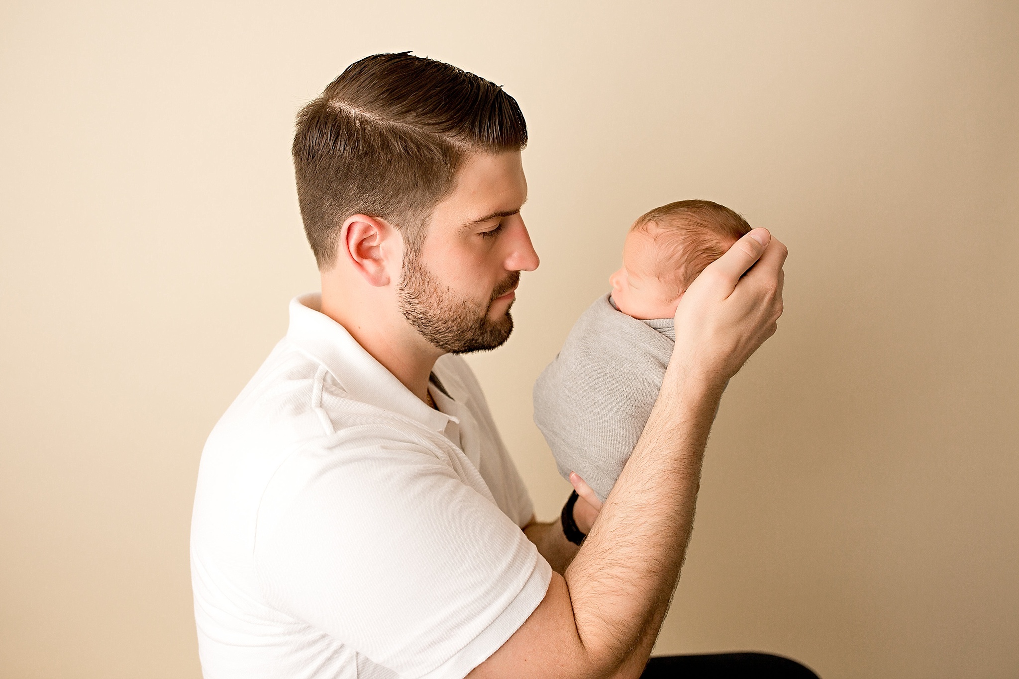 father looks at new baby boy during newborn session