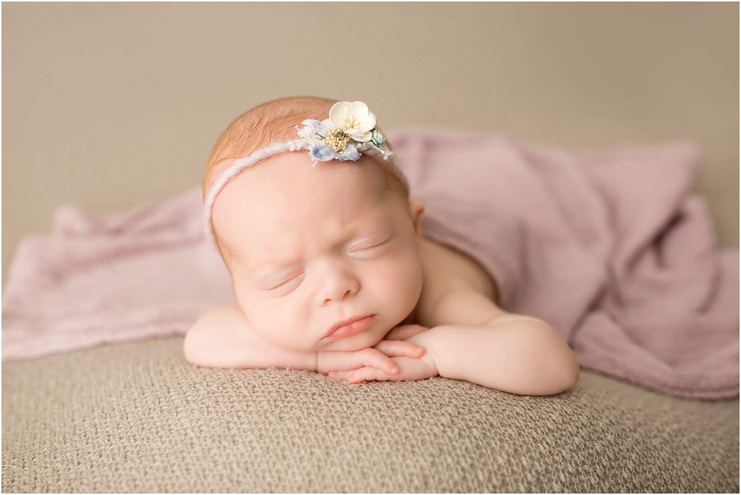 Newborn girl in chin on hands pose
