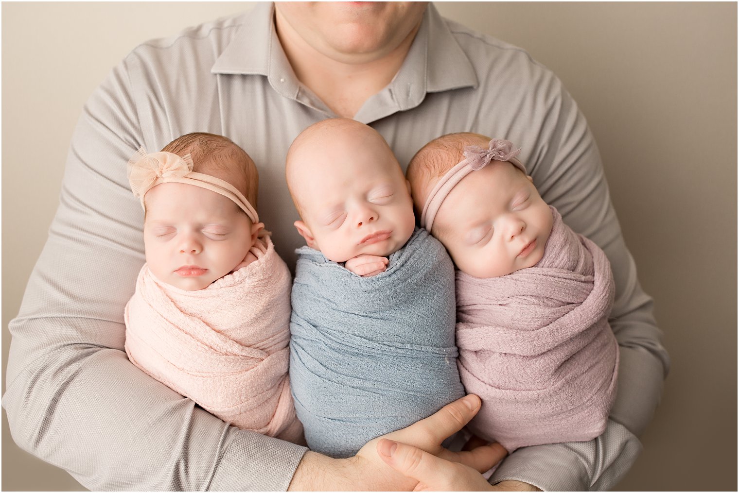 father holding newborn triplets