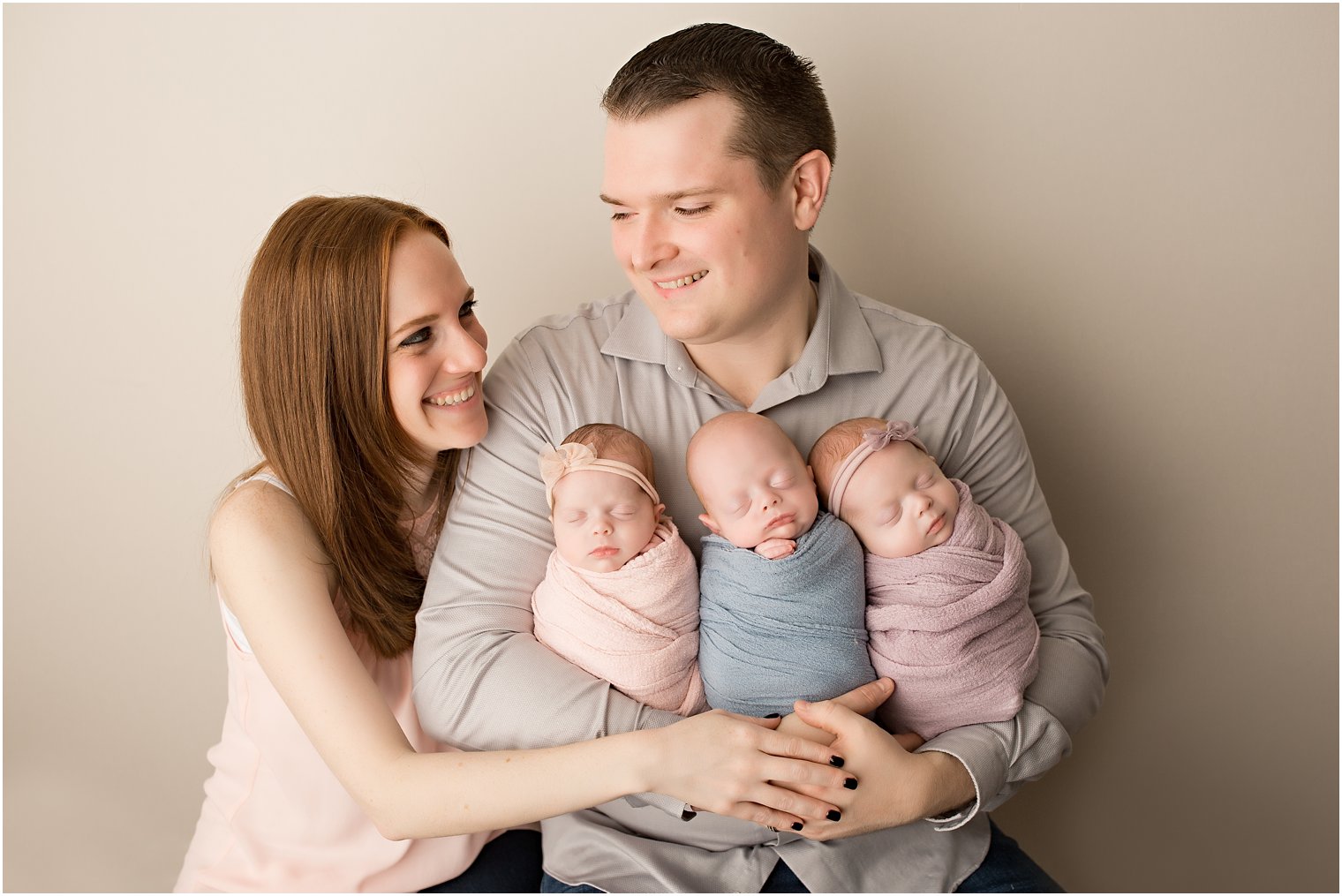 Parents holding newborn triplet babies