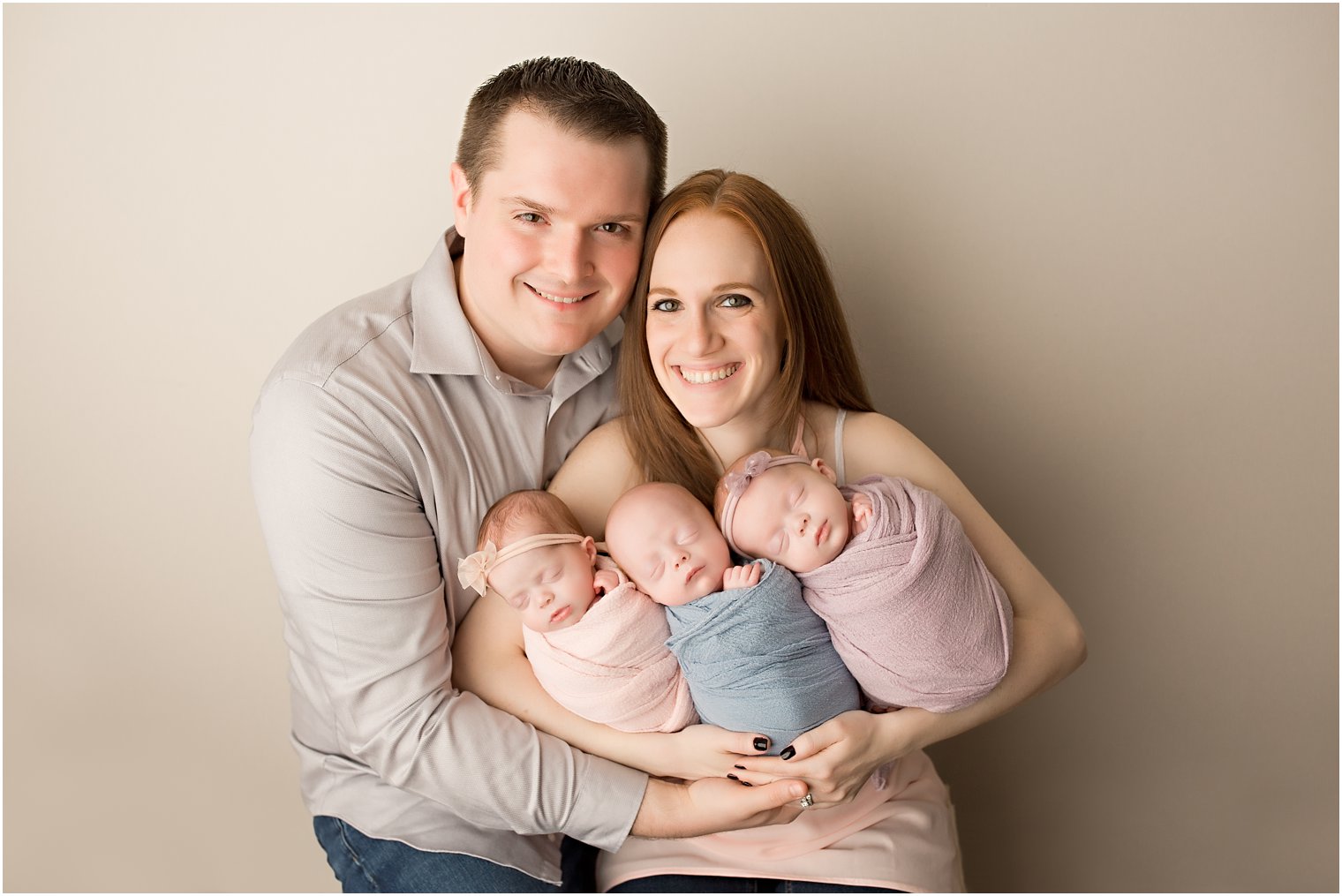 parents holding newborn triplets