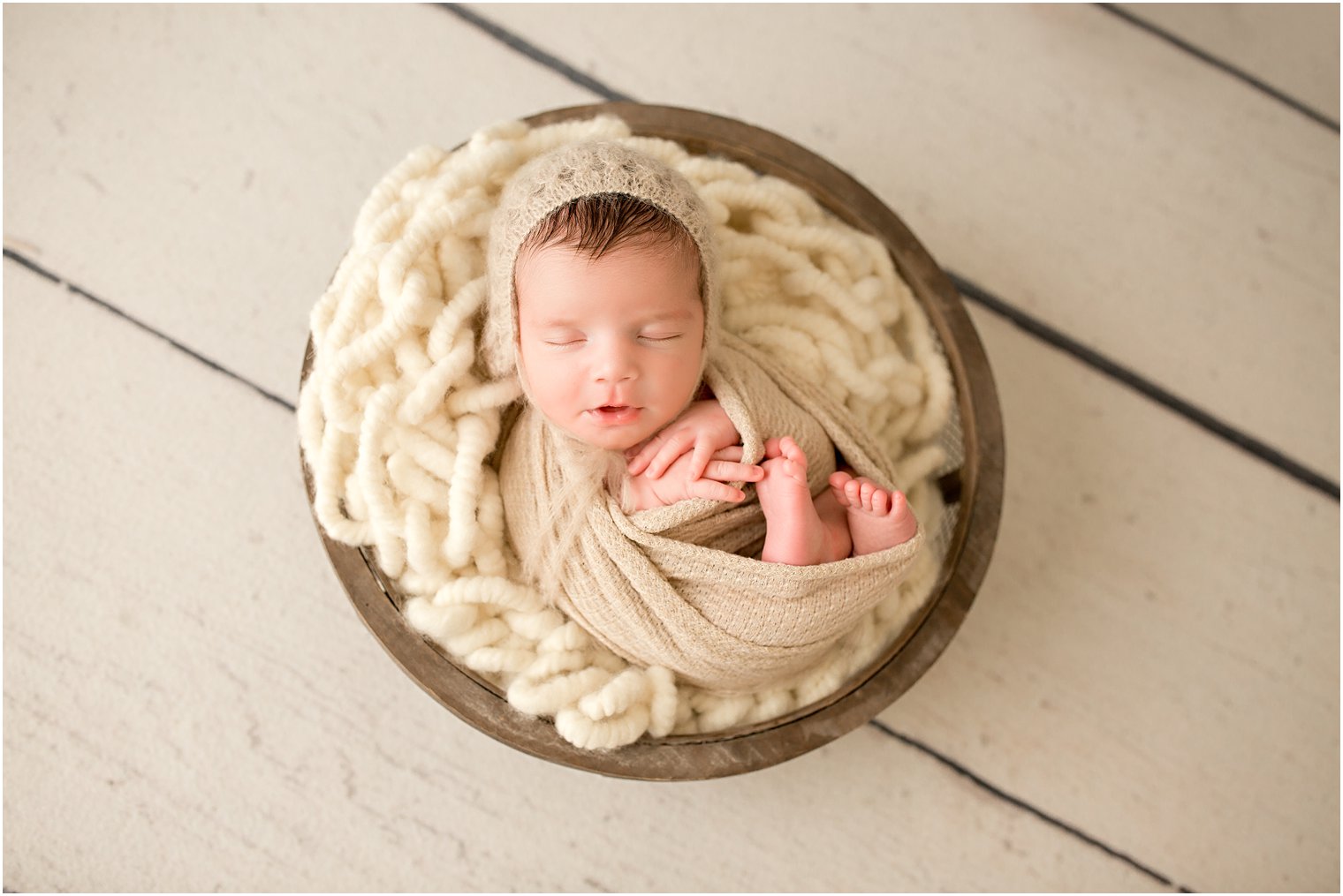 newborn boy on a cream wooden floor