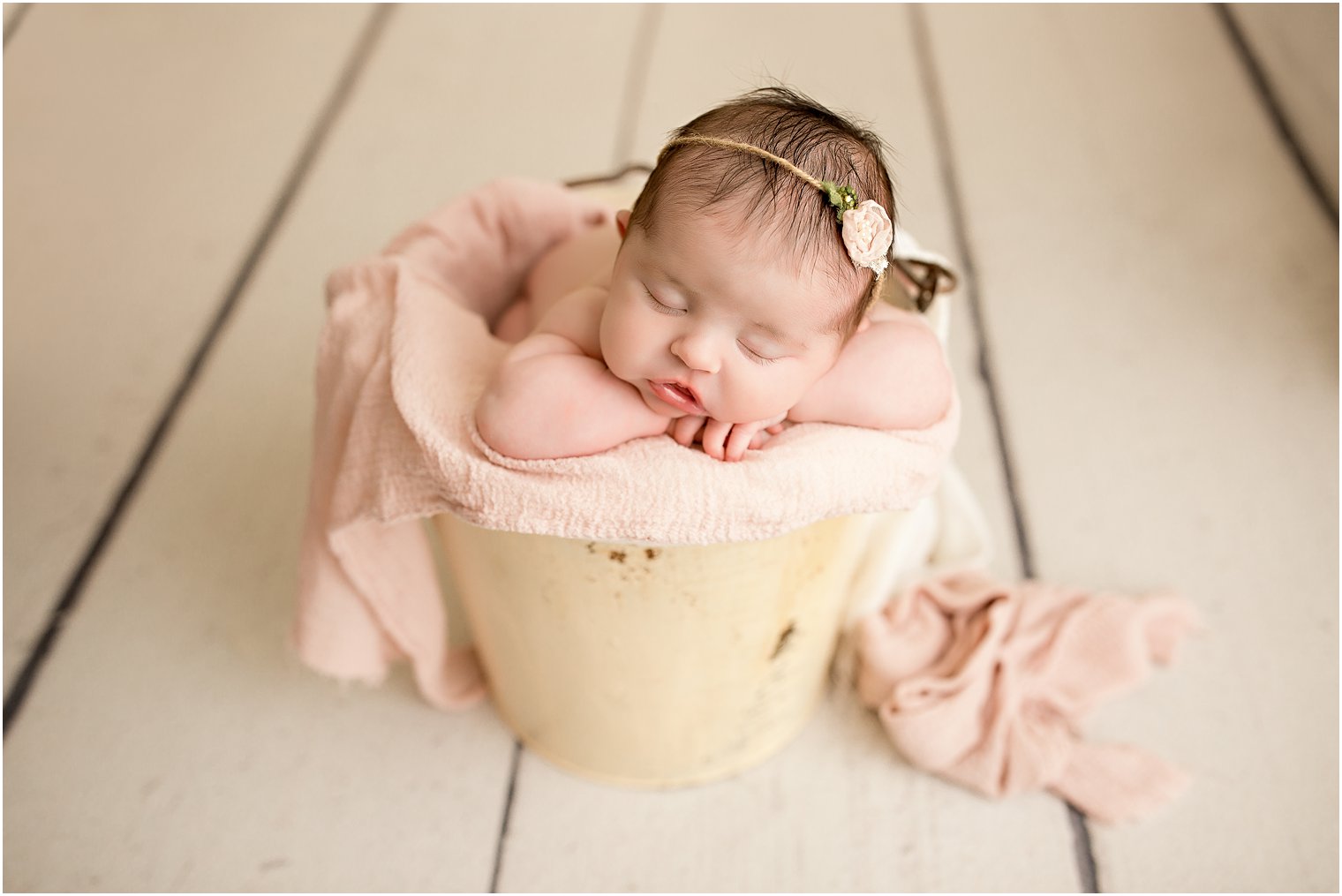 newborn girl in a beige bucket