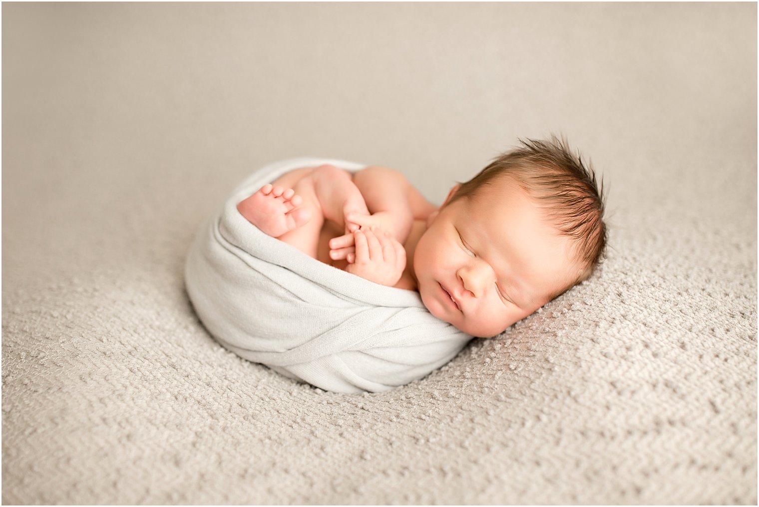 newborn boy swaddled in gray