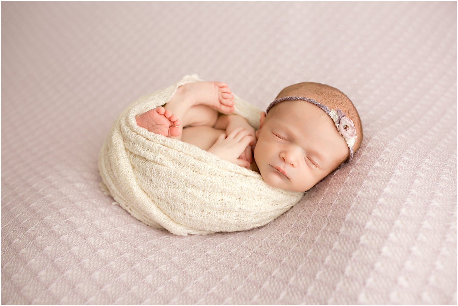 newborn girl swaddled in a beige blanket