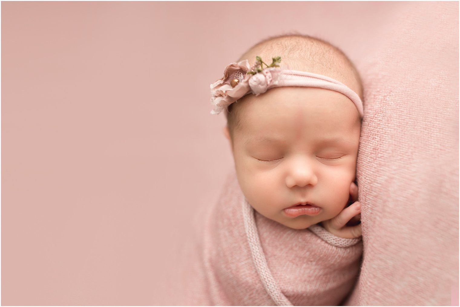 sleepy newborn on pink blanket
