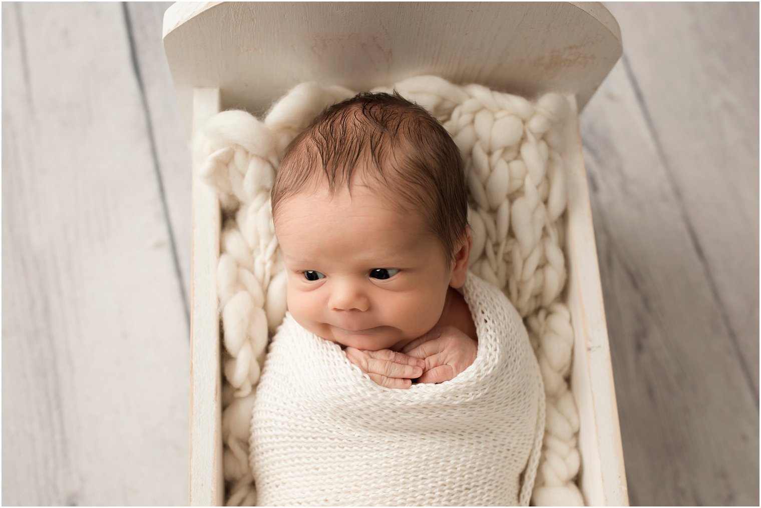 newborn boy in a tiny wooden bed