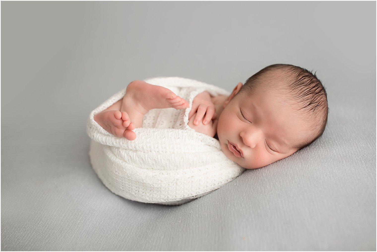 Newborn boy on gray blanket