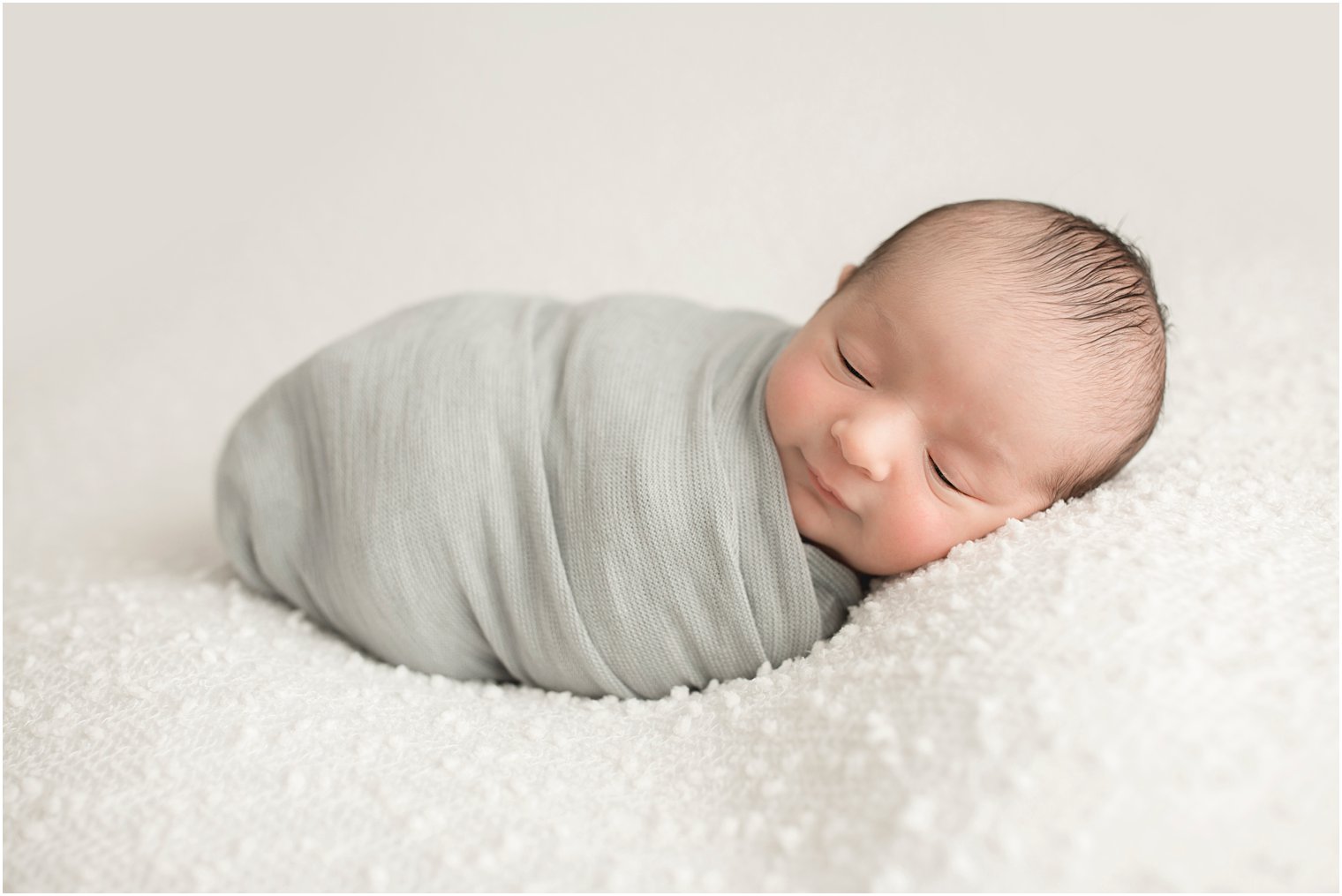 Newborn boy wrapped in gray swaddle