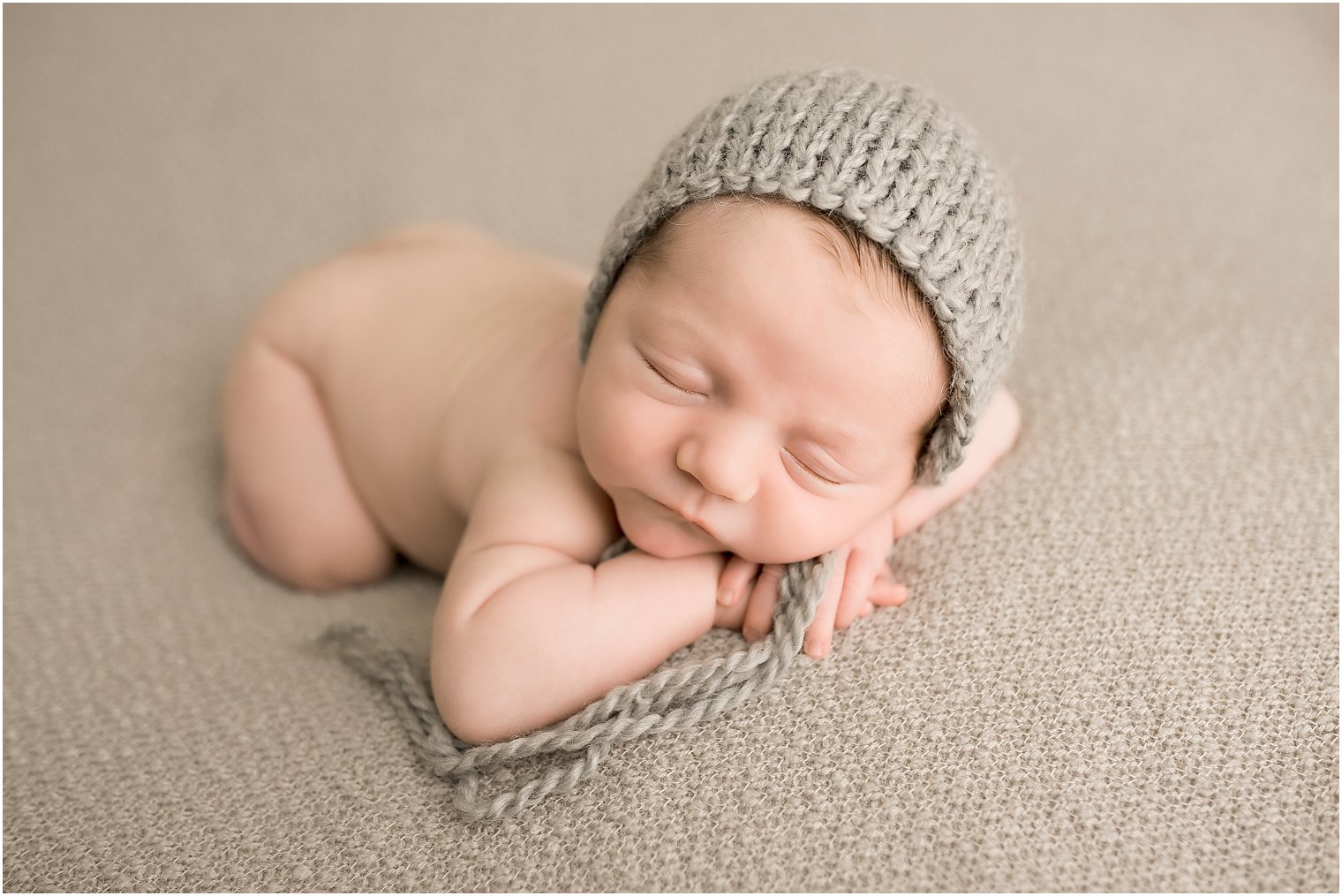 Sleeping newborn boy in gray hat | Photo by Idalia Photography