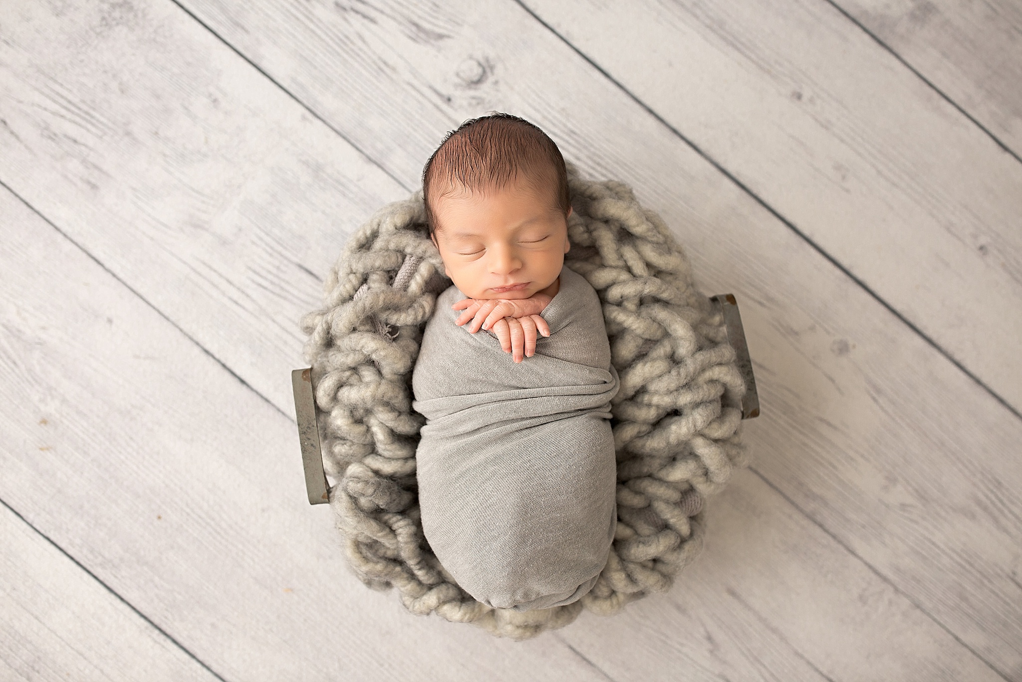 sleeping baby boy newborn in basket with chunky grey basket