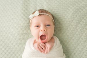 baby-girl-yawning-on-green-blanket