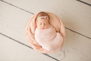 baby-girl-sleeping-in-basket-with-peach-wrap