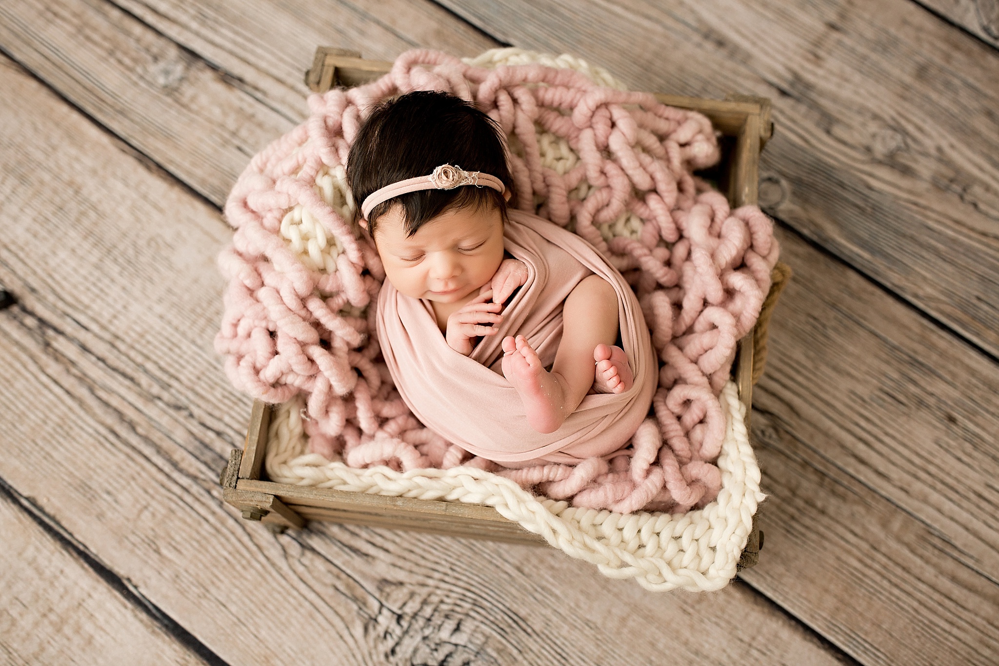 newborn baby girl in box with pink blanket