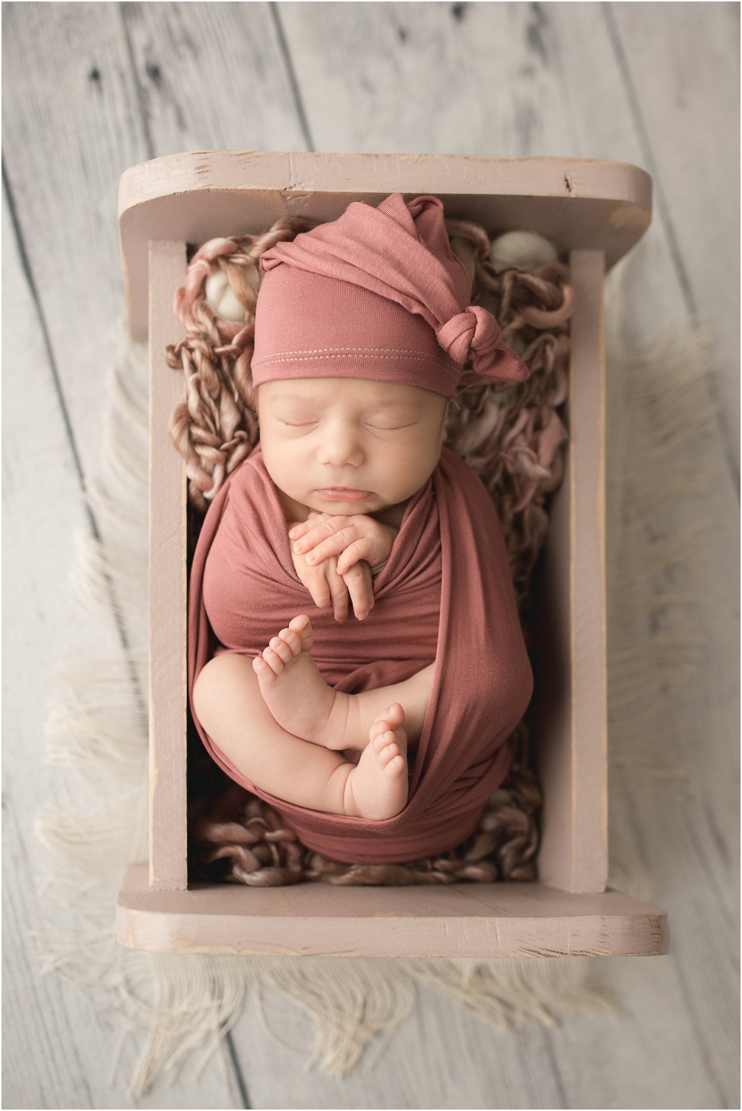 newborn girl in pink wooden bed